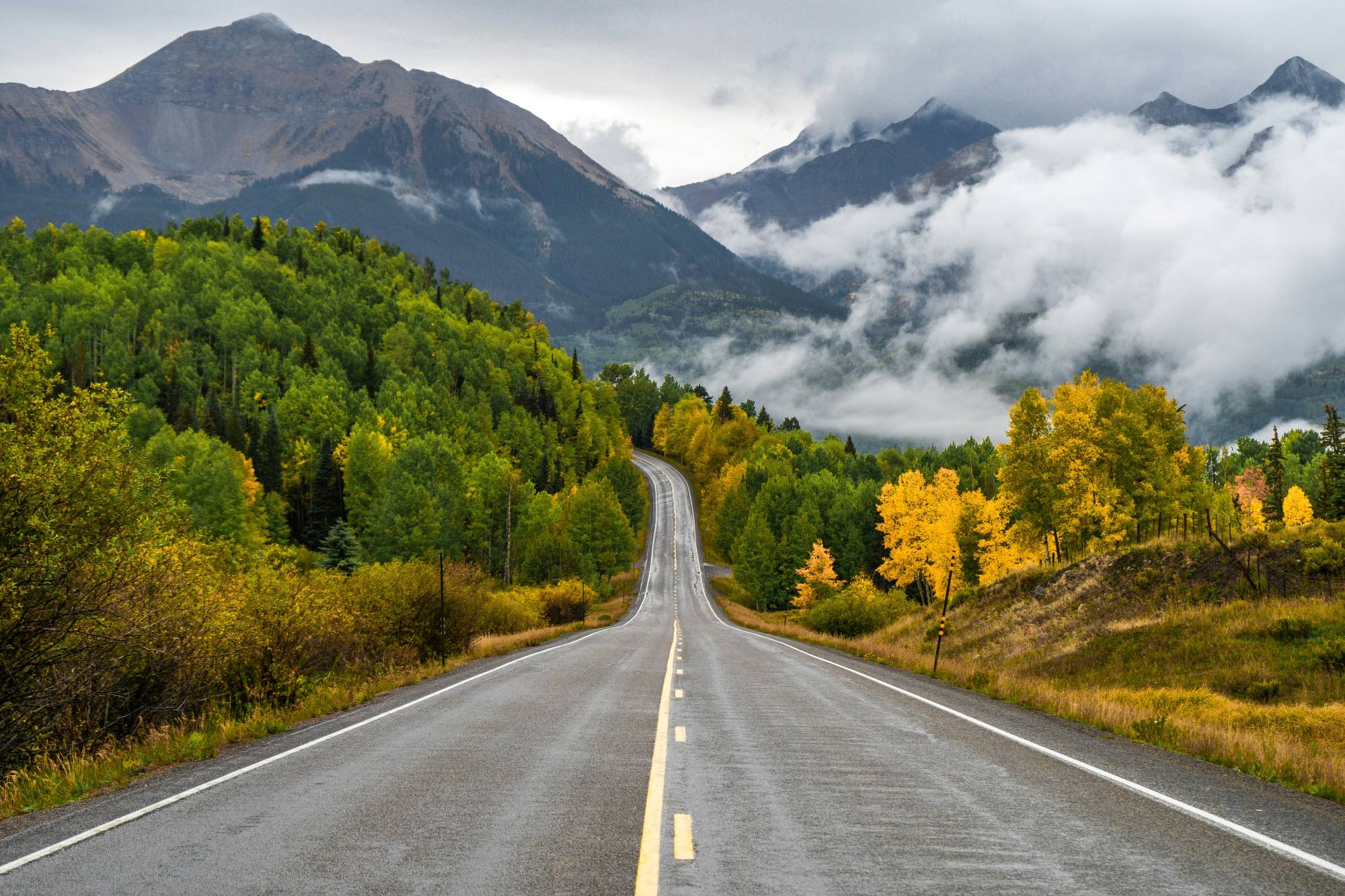 Beautiful mountain road surrounded by colorful fall foliage and misty mountains.